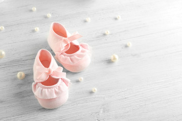 Baby booties on wooden table, closeup