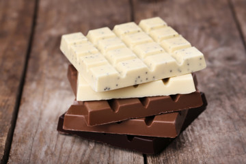 Different chocolate bars on wooden background