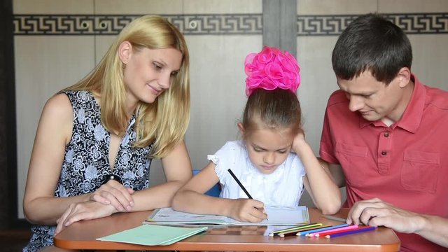 Schoolgirl doing homework with their parents smile looked into the frame