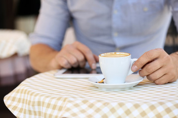 Businessman drinking coffee and using tablet in cafe