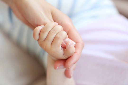 Woman holding small baby hand
