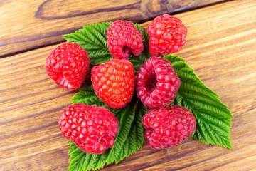 Fresh, ripe raspberries on leaves, rustic wooden background