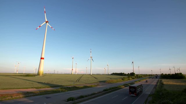 Wind turbines in front of a highway.