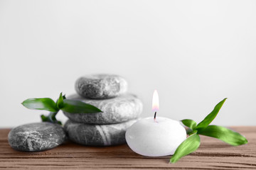 Obraz na płótnie Canvas Gray spa stones with candle on light background
