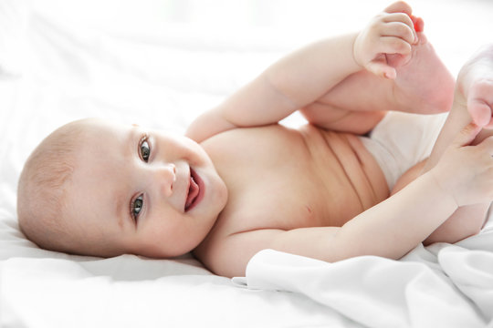 Smiling adorable baby on white bed