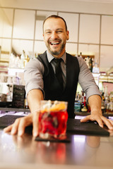 Barman is making cocktail at night club.