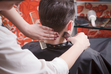 Closeup picture of barber girl using hair clipper for making handsome man' hair cut in hairdressing saloon. Hairdresser using hair clipper for hair.