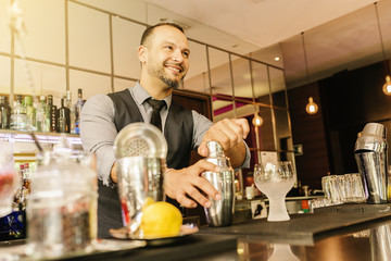Barman is making cocktail at night club.