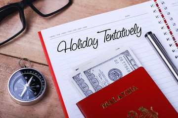 Vacation tentatively text message on note book with passport, glasses, hundred dollar bills,...