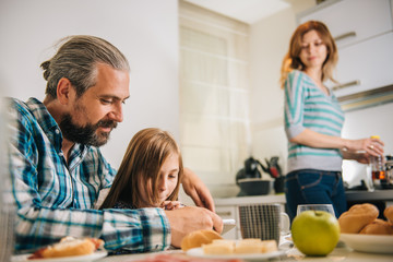 Father and daughter using tablet in the kitchen