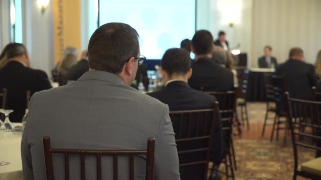 A suited man attends a conference