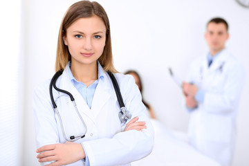 Friendly female doctor on the background with patient in the bed and his doctor