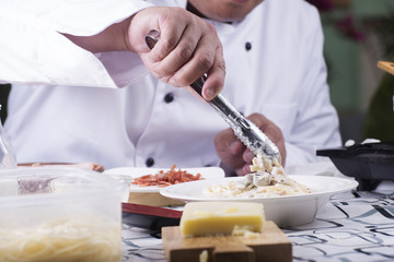 Obraz na płótnie Canvas Chef decorated Spaghetti carbonara to the plate with tongs