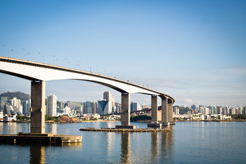 bridge over sea and city skyline against blue sky