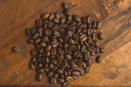Brown coffee beans in circle shape, closeup of macro coffee beans for background and texture. On brown wooden board with magnify glass. Copyspace