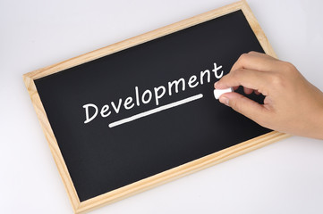 Women Hand Holding Chalk Writing "Development" Word On Black Board