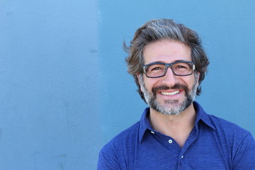 Portrait of stylish businessman with glasses smiling on blue wall background with copy space © ajr_images