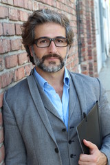 Portrait of mature business man with grey beard and hair alone outside modern creative office