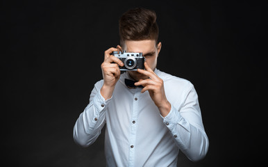 Handsome young man with a camera in his hands. Photographer's work. Festive photo. Photos creativity