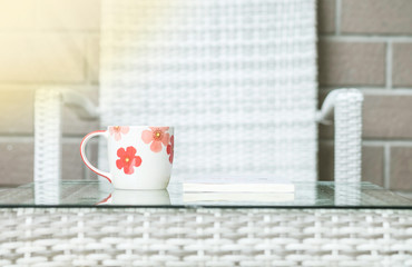 Closeup cute cup on blurred wood weave table and chair textured background
