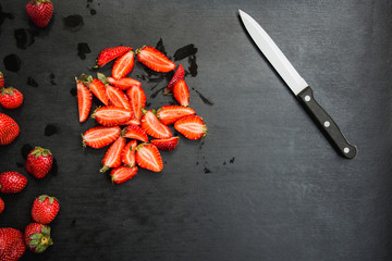 strawberries and knife on black background