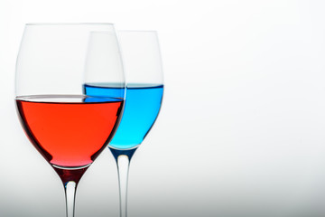 two glasses with blue colored water and wine