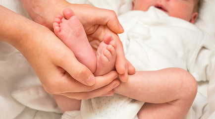 Fototapeta na wymiar Baby legs. Legs newborn in sister hand