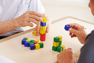 Hände von Senioren mit Demenz bauen Turm