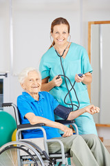 Seniorin im Rollstuhl bei Blutdruckmessung