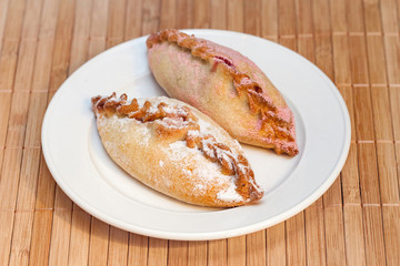 Two sweet pasties stuffed cottage cheese on bamboo napkin