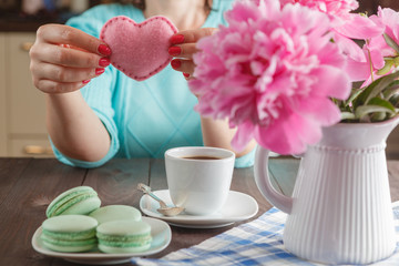 Woman drink coffee and holding in hands soft heart shape