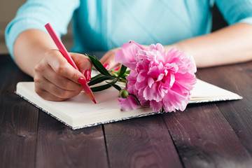 Obraz na płótnie Canvas Pink peonies in woman hands on aged wooden table