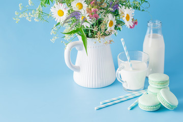 Glass of milk with striped straw and macaroons.