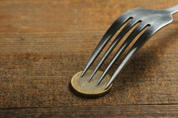 penny prick with a fork on a brown wooden background.The concept of poverty