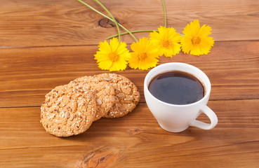 Cup of cappuccino cookies and flowers on the table.