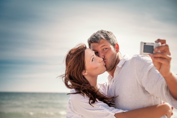 Obraz premium happy couple taking selfie on beach