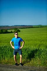 man runner athlete jogging along a green field in the early morning. man fitness sunset jogging workout wellness concept. free space in front of the person