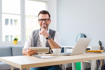 Happy man at home office working on laptop