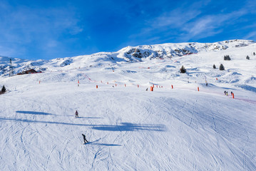 Fototapeta na wymiar Unidentified skiers enjoy skiing at the slope in the Alps. Ski