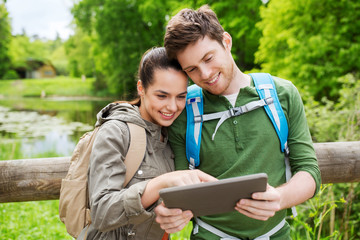 happy couple with backpacks and tablet pc outdoors