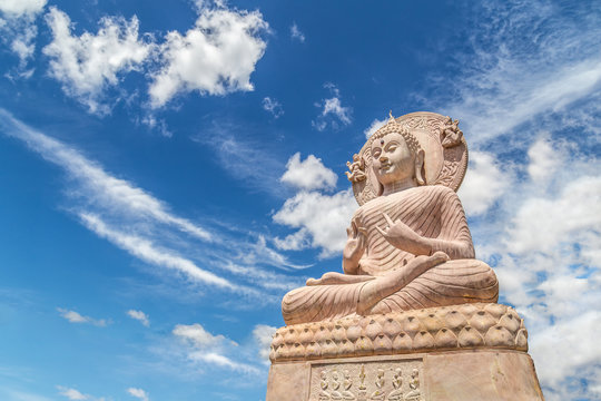 Carved sandstone Buddha statue on blue sky background