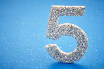 Number five silver color over a blue background. Anniversary.