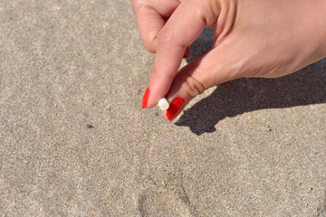 Women hand extinguish cigarette into the sand of a beach. Quitti