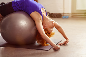 frau dehnt sich über einen ball im fitness-studio