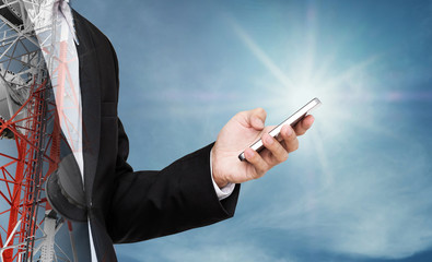 Businessman using mobile phone, with double exposure telecommunication tower on blue sky with sunshine