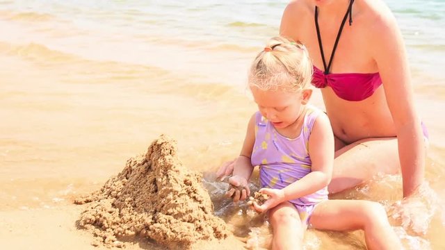 Mother Little Daughter Build Sand Castle on Beach of Azure Sea