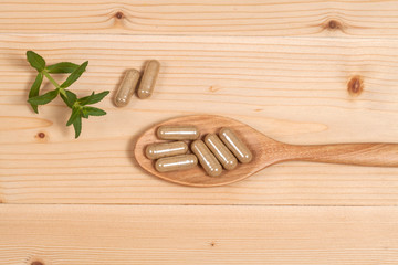 Herbal capsules on wooden spoon. herb for healthy