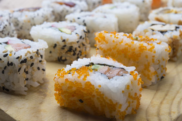 Different Sushi rolls,wasabi and ginger on a plate on wooden bac