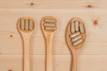 Herbal capsules on wooden spoon. herb for healthy
