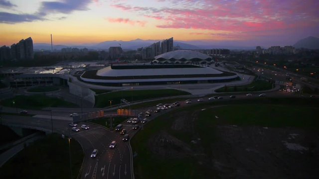 Vertical lift over stadium and city freeway at sunset
